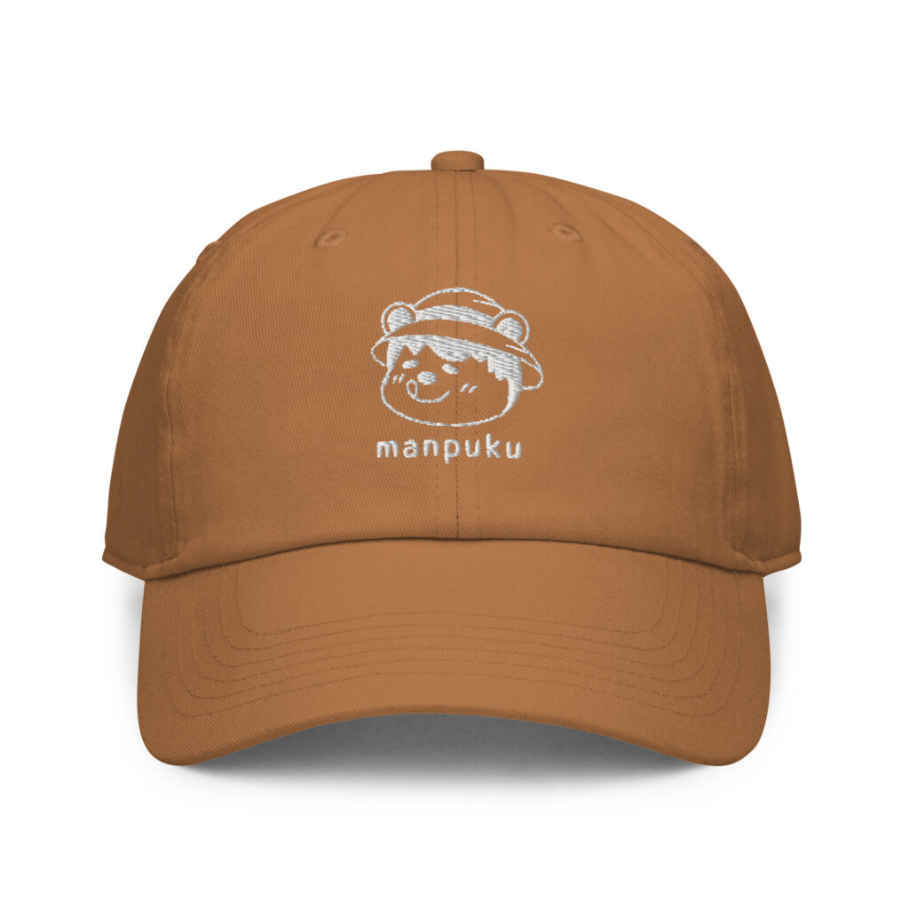 夏八木敦也さん描き下ろしの“まんぷくくま”イラストを白い刺繍で入れたブラウンのキャップ。満腹で幸せそうな表情のくまと“manpuku”の文字が刺繍されている。